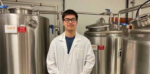 Mathew Li standing in front of reaction tanks