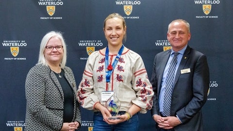 Olga Shmaidenko holding her award, beside Chris Houser and Kirsten Muller