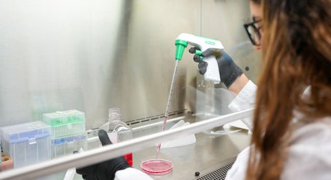 A science student using a pipette in a lab.
