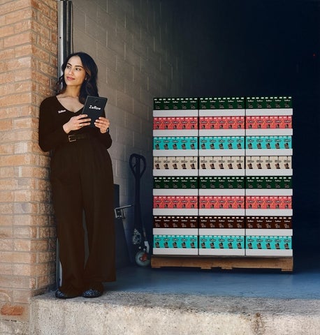 Gigi Gill at her shipping warehouse with boxes of her product behind her.