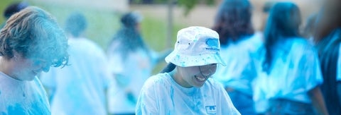 A student wearing a white bucket hat celebrating Science Day in the blue powder.