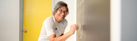 Tan Dinh, senior lab instructor, at a chalk board in his lab. 