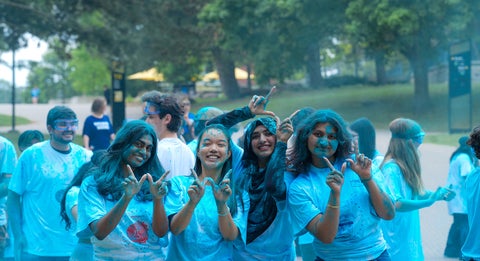 Four Science students posing and making a "W" symbol. They are covered in blue powder.