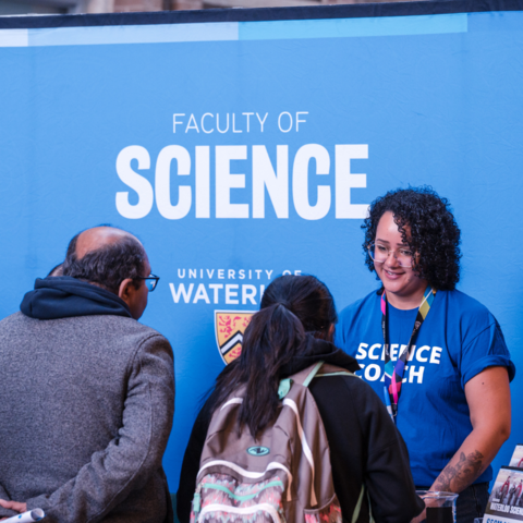 A Science staff member greeting students at an open house. 