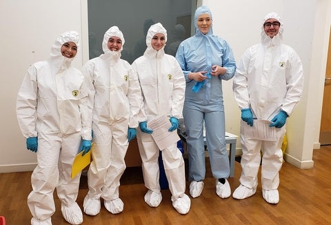 Students dressed in body suits to perform forensic science activities.