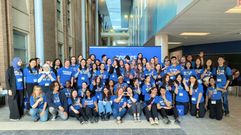 A large group of students wearing blue Science t-shirts in front of a Science sign. 