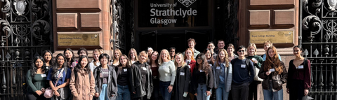 A group of Waterloo Science students standing outside in front of a sign that says "University of Strathclyde Glasgow".