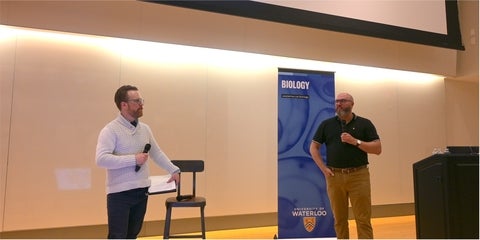 Travis Craddock and Dale Martin talking with microphones at the front of a lecture hall