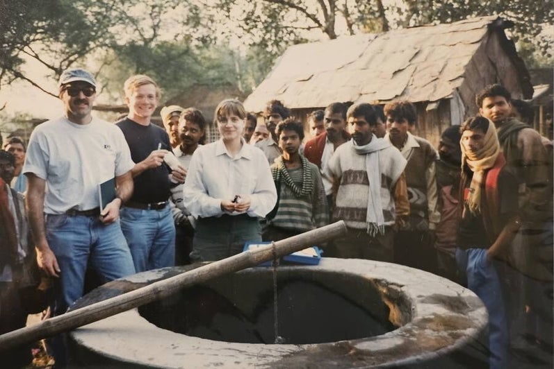 Shaun Frape, alum Rebecca Jacketeit, and a group of people standing around a well on a field site