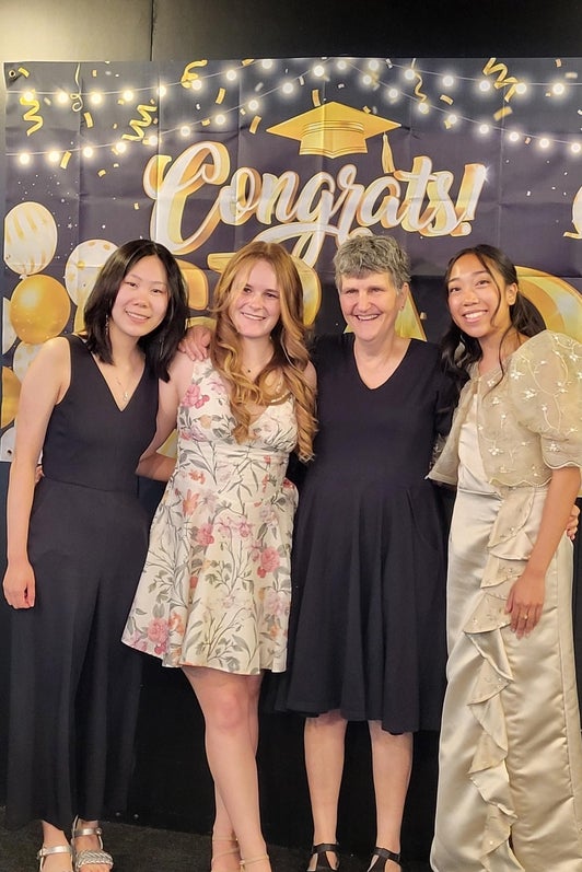 Chemistry students posing with professors of Chemistry in front of a graduation sign. 