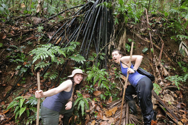 Two students striking a pose in a rainforest.
