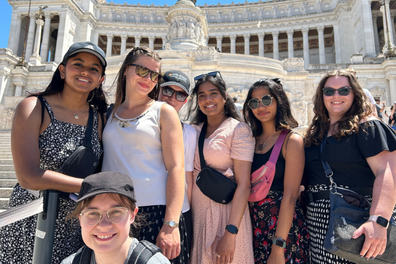 Seven students standing on the steps in front of Altare della Patria in Rome.
