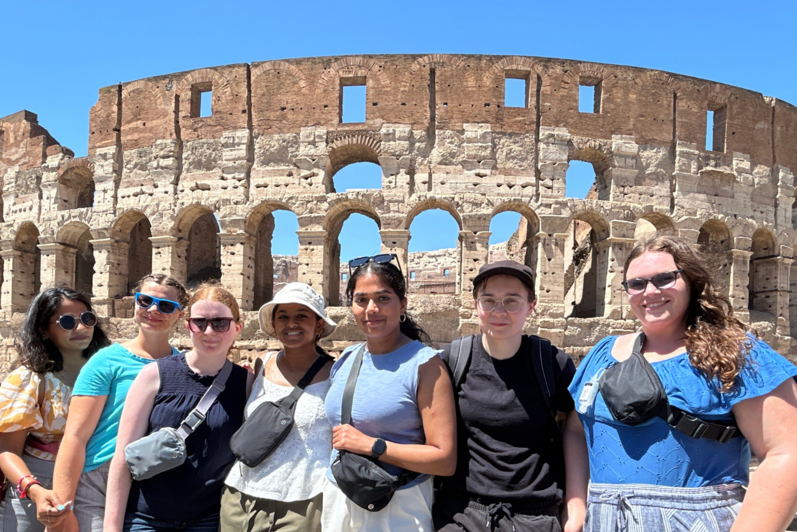 Seven students standing in front of the Colosseum in Rome. 
