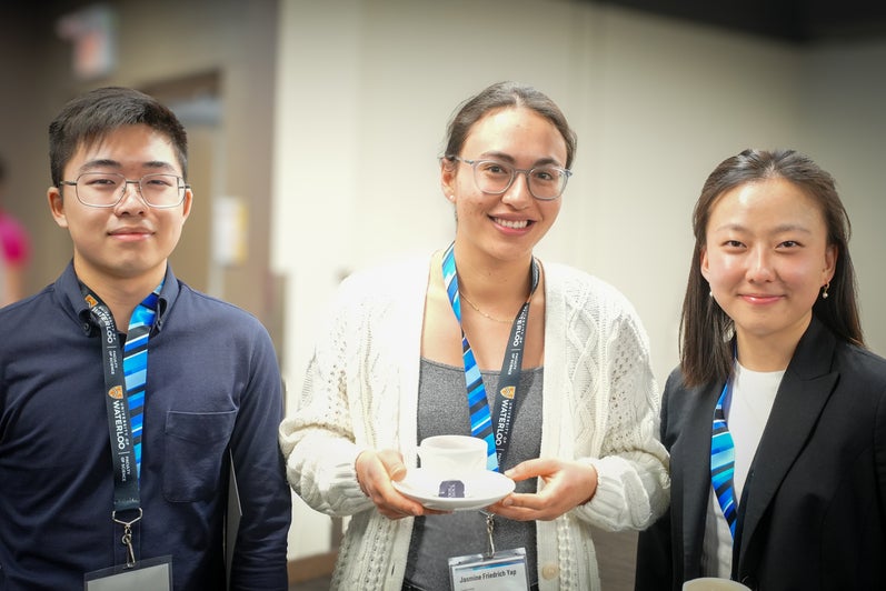 Three students wearing blue science lanyards in a banquet hall.