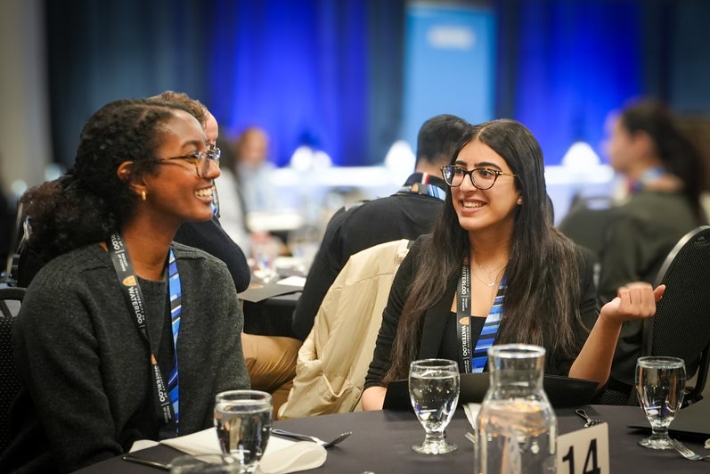 Two students wearing blue science lanyards in a banquet hall.