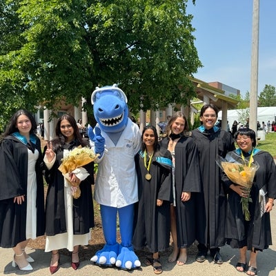 Cobalt surrounded by a group of 6 new graduates wearing their convocation gowns and hoods