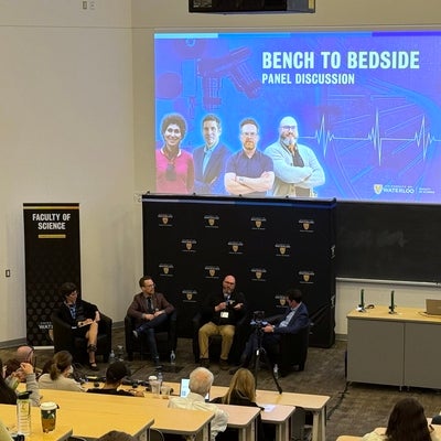 A panel discussion at the front of the room with an attentive audience looking on