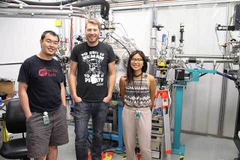 Three researchers standing in front of a metal contraption at the Canadian Light Source