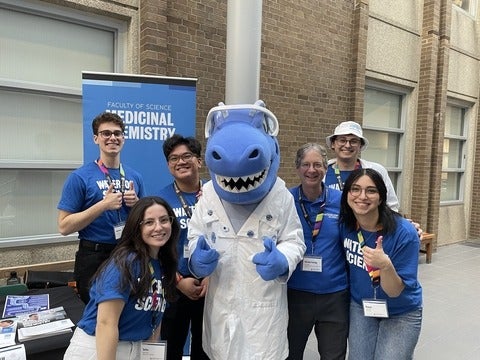 A group of science students with cobalt the dinosaur in the middle.