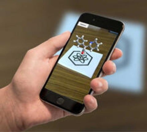 Cell phone with image of 3D chemical models projected above the 2D paper representation.