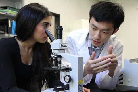 Two students talking over a microscope.