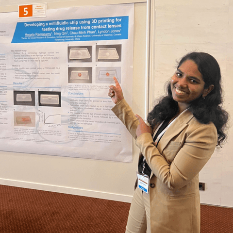 Megala Ramasamy standing in front of research presentation board