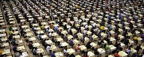 Mass number of students sitting at desks writing exams.