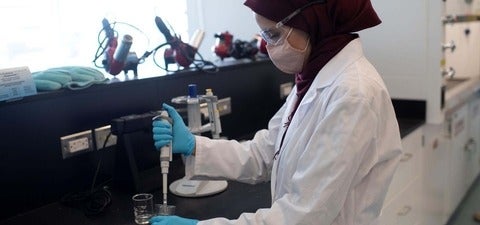 Female scientist pipetting a fluid into a beaker,