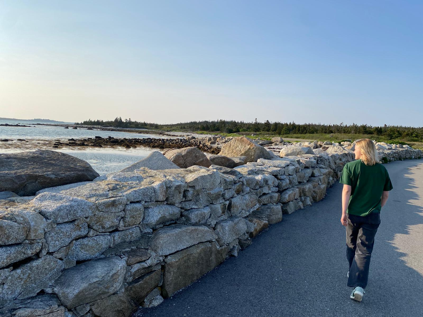 Maya walking on a paved pathway along the coast of Nova Scotia. 