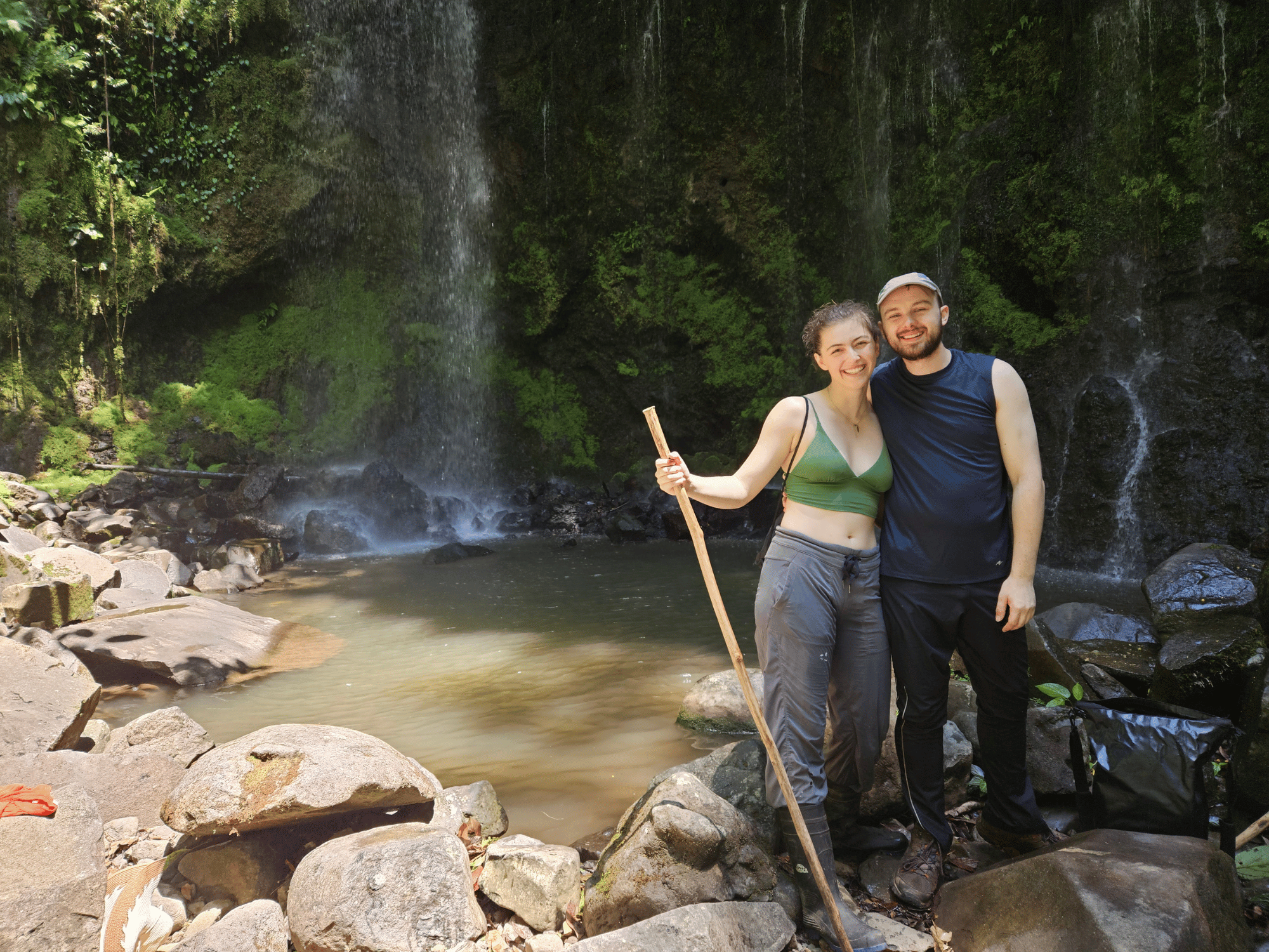 Daniel and Liv standing next to a waterfall and swimming hole.