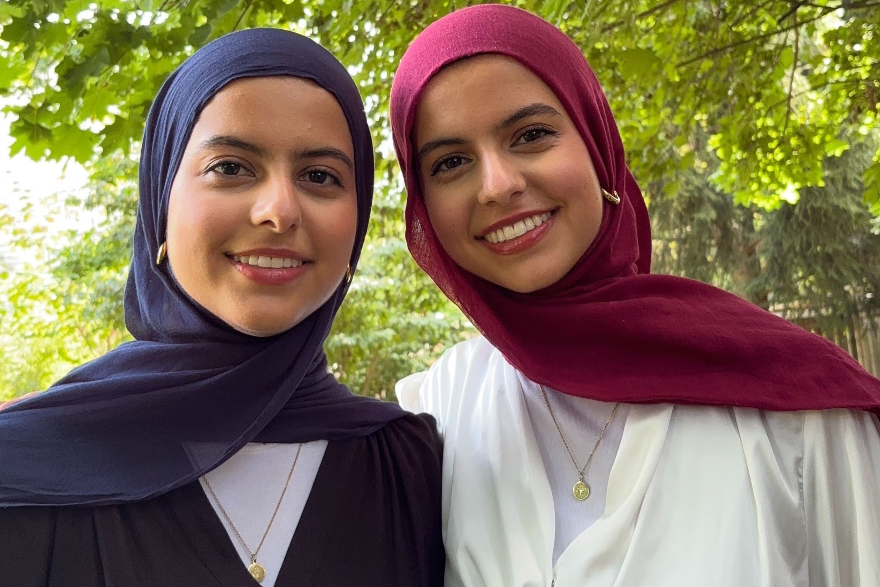 Twin sisters Marwa Al-Hammadi and Mawada Al-Hammadi smiling, surrounded by nature.