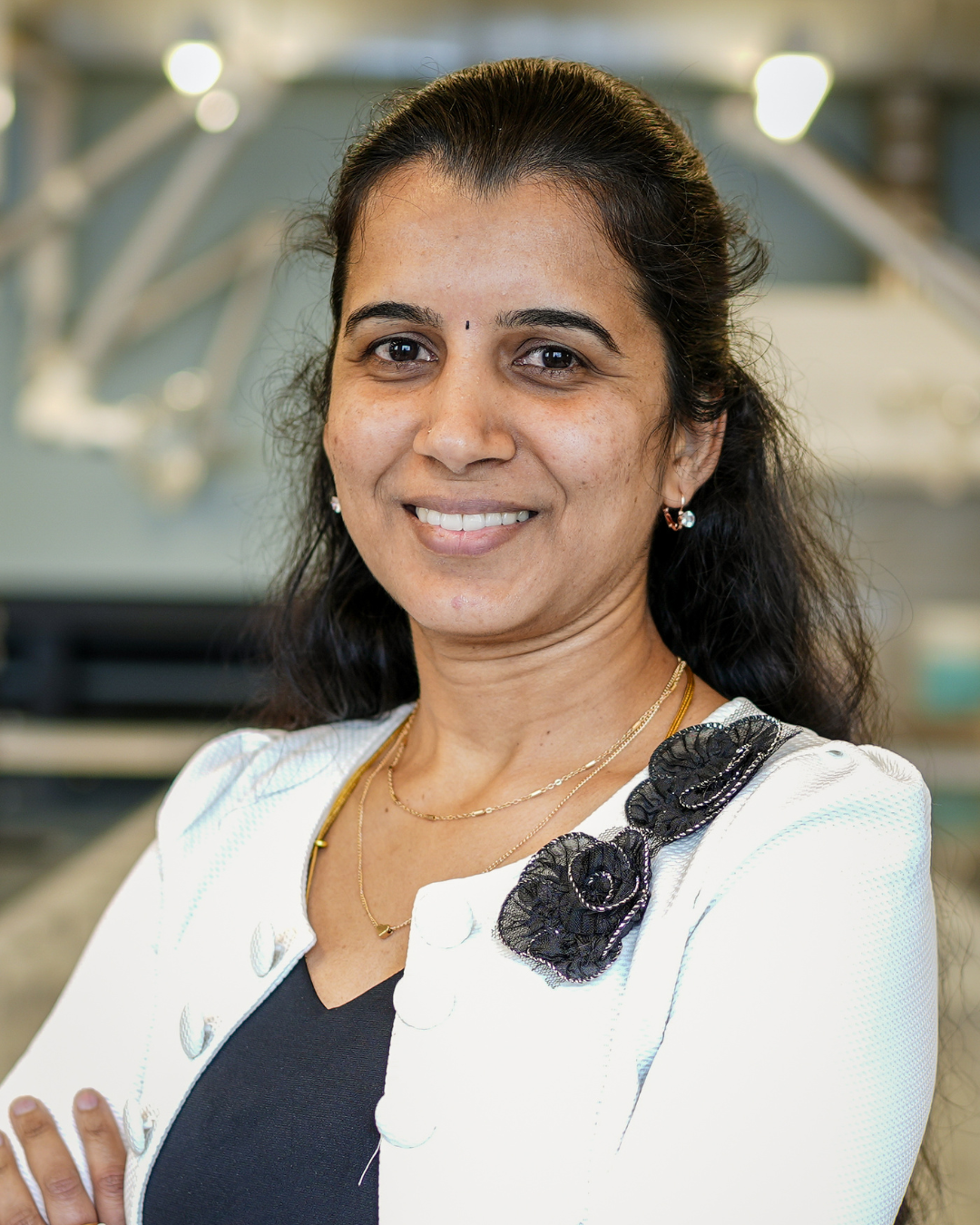 Subha Kalyaanamoorthy is a Professor of Chemistry in the Faculty of Science. She is wearing a white cardigan and his posing with her arms crossed.