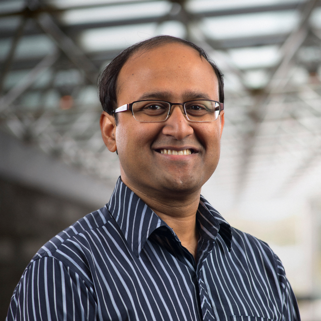 A headshot of Dr. Rajibul Islam. He is wearing a blue striped collared shirt and has glasses on. 