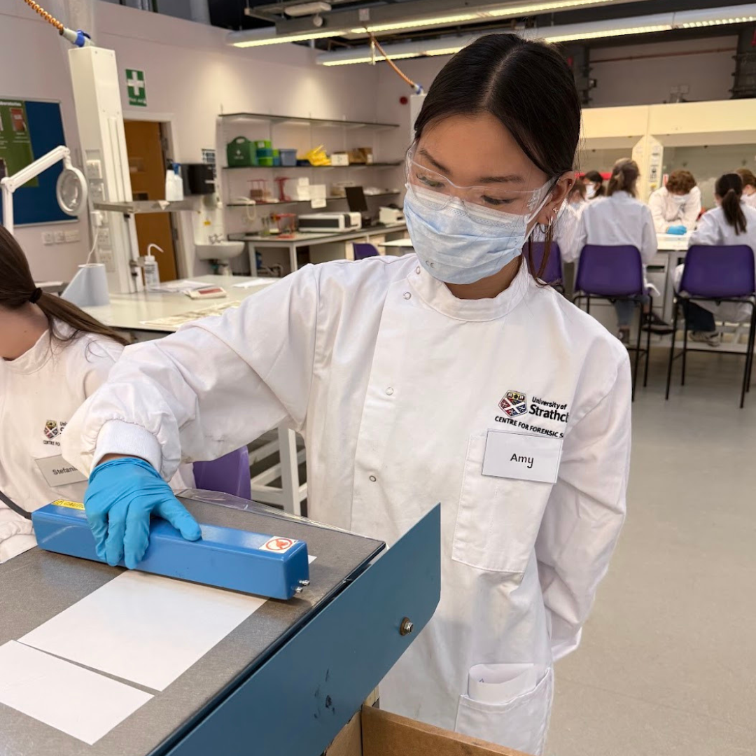 Amy wearing a white lab coat and blue gloves conducting an experiment.