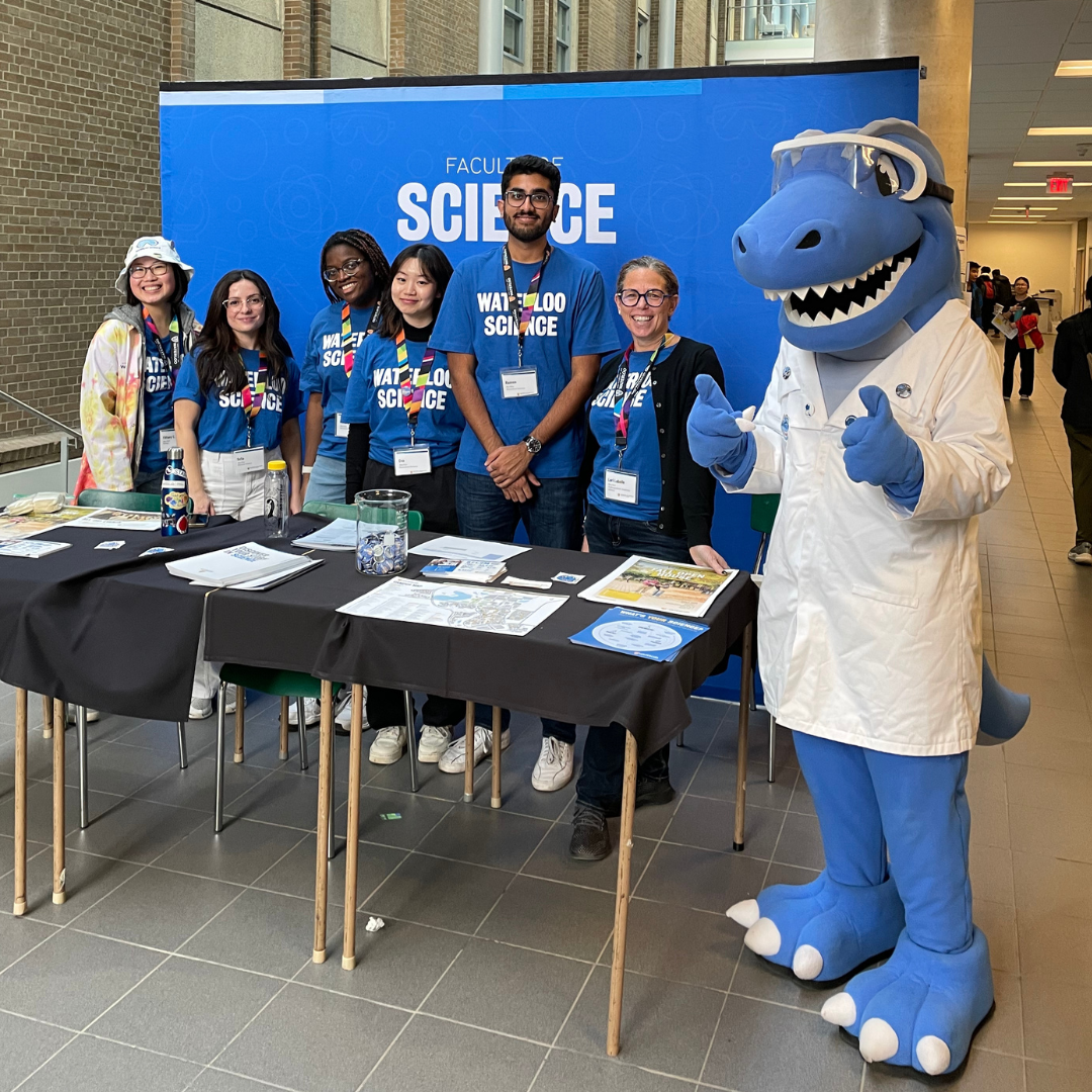 Science students stand in front of a blue "science" background. Cobalt the dinosaur is standing next to them with his thumbs up. 