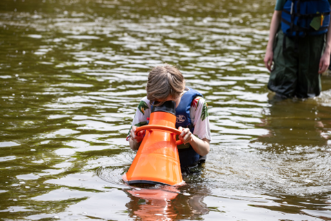 Student using a piece of equipment that looks at bugs in the water.