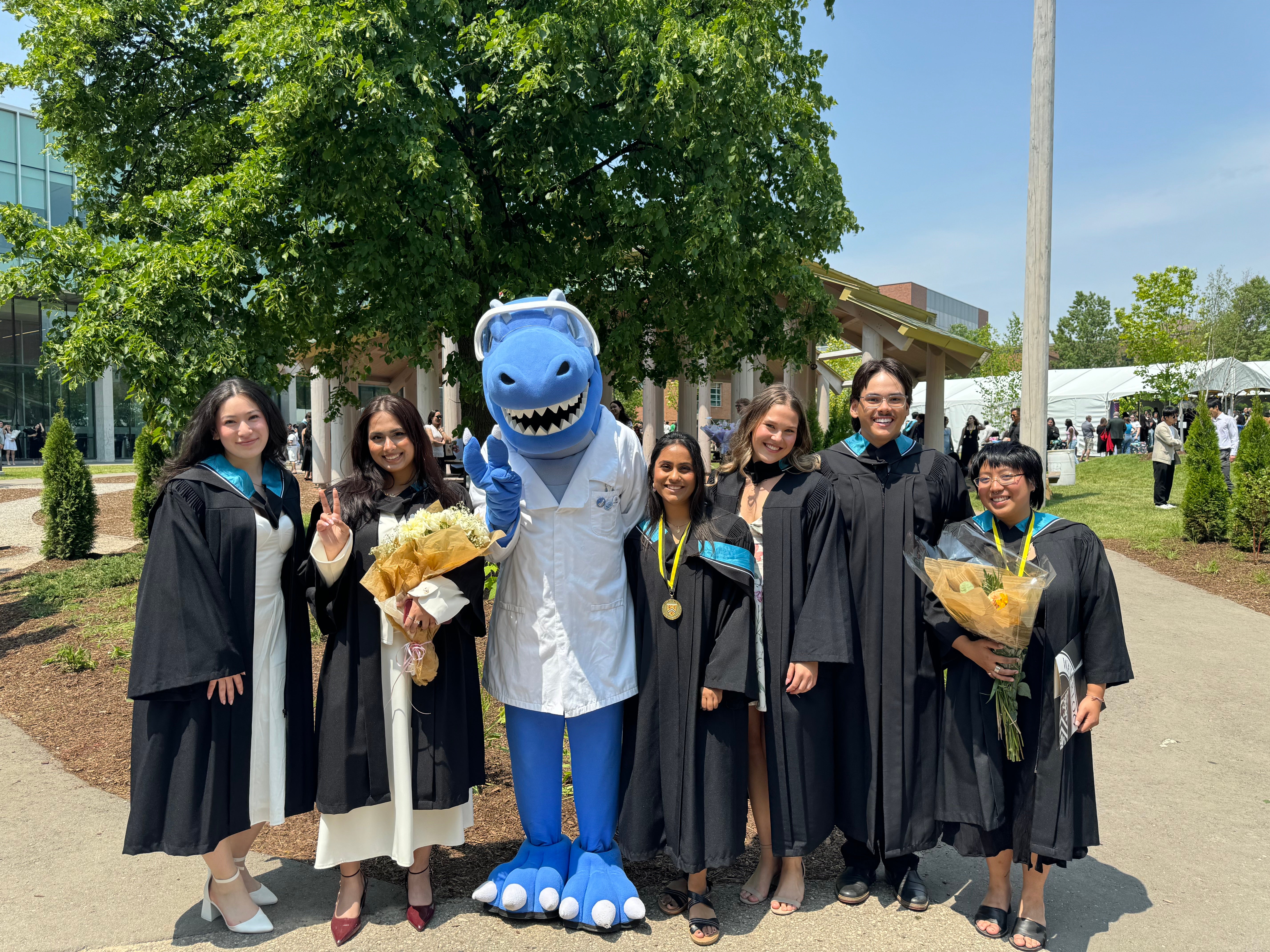 Cobalt surrounded by a group of 6 new graduates wearing their convocation gowns and hoods