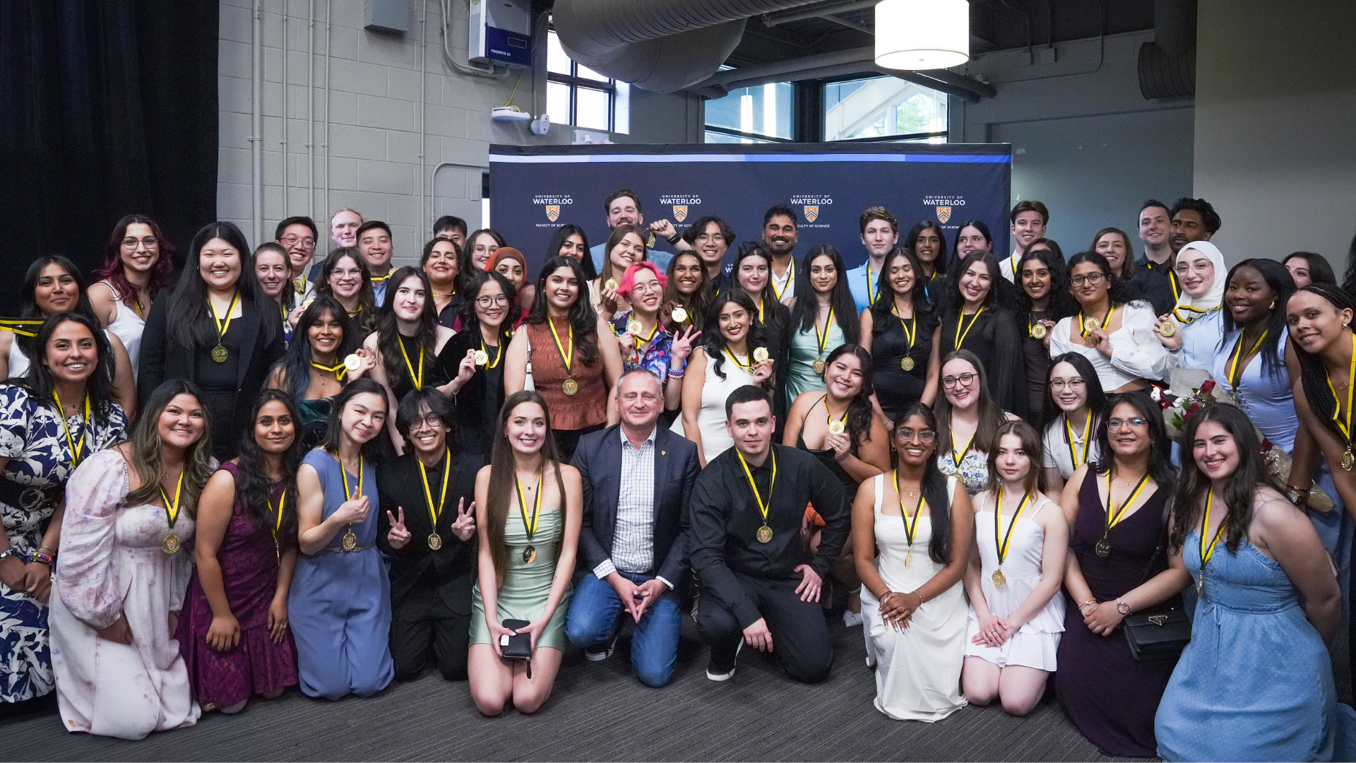 Dean Chris Houser kneeling in the middle of a large group of IDEAL Scholar students.