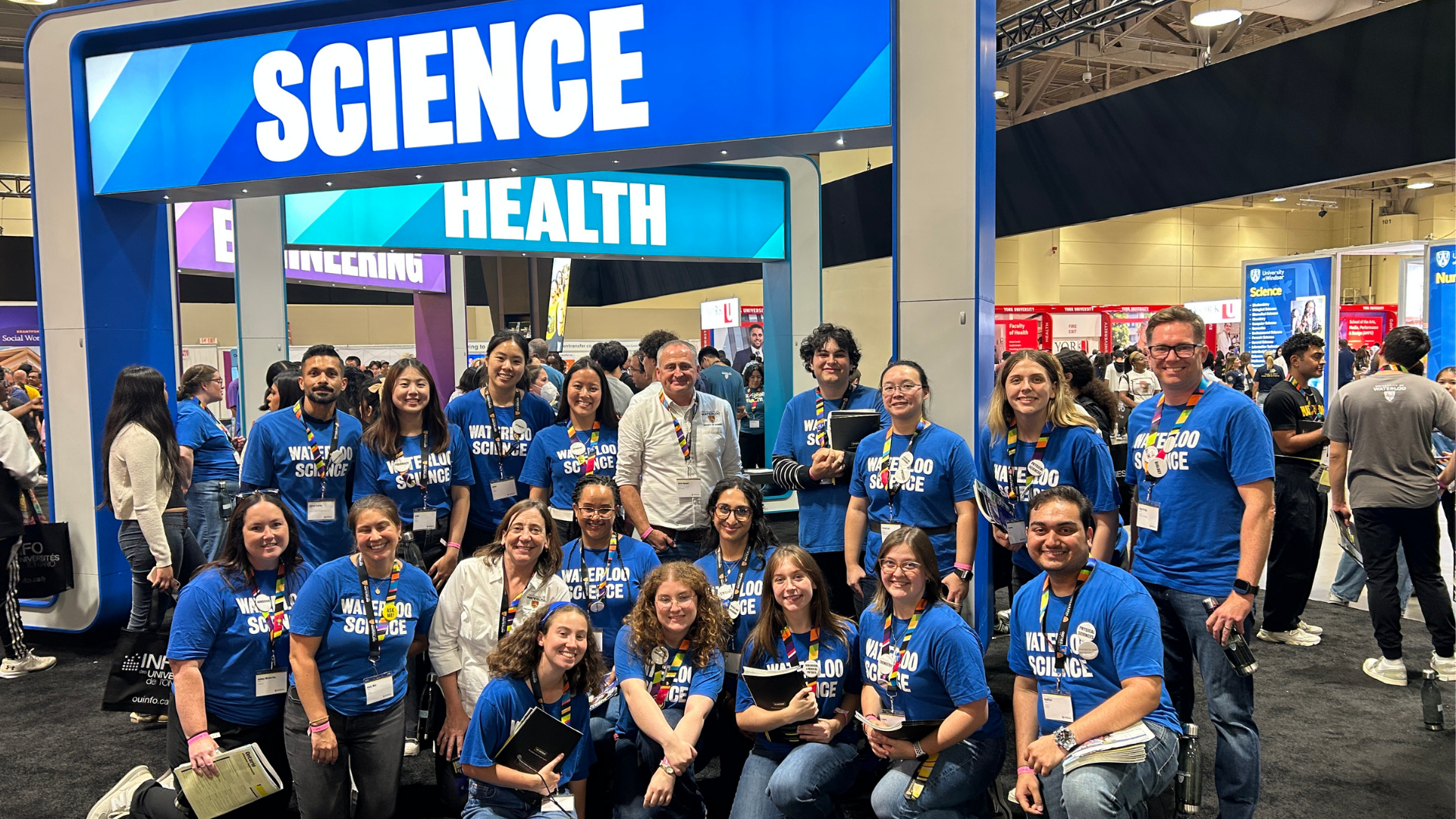 Dean Chris Houser standing in the middle of a group of Science students who are wearing blue t-shirts at the Ontario Universities Fair. 