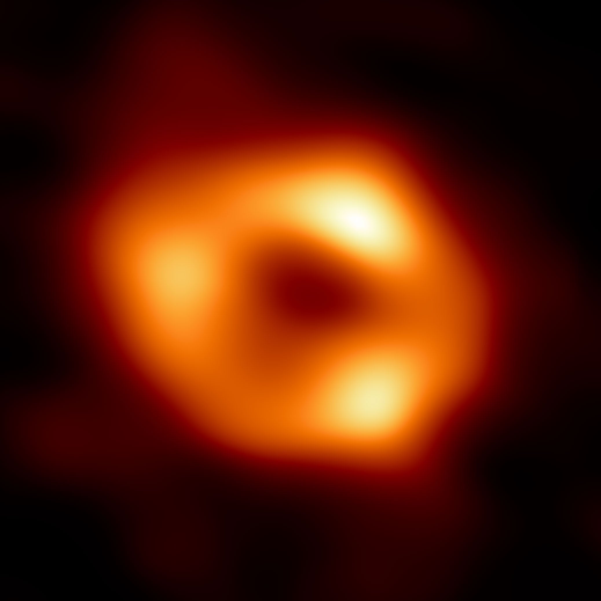 A bright orange ring with three very bright spots almost equally spaced along the ring. Smudges of orange light extend from the ring towards the edges of the image