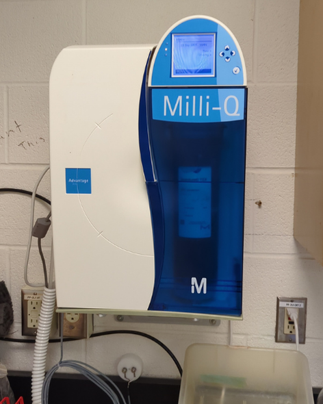 A wall-mounted blue and white instrument branded Milli-Q, with rubber tubes coming out of it.