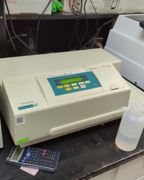 A rectangular benchtop instrument, with the brand Spectramax plus. A small screen is on the front centre of the machine, with 8 buttons including temperature and wavelength settings, and a large hinge door is on the machine to the right side.