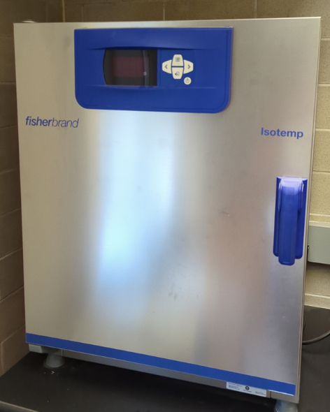 A rectangular tabletop instrument with a shiny silver front. There is a blue handle on the right side of the front, as well as a blue panel display with a screen and four arrow buttons at the top of the front face, and a hinge on the left side. The instrument says fisherbrand isotemp.