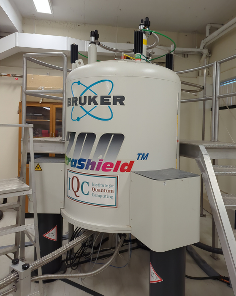 A large cylindrical machine sitting on the floor, with a stepladder beside it to reach the top. The brand Bruker is visible, alongside the number 700.