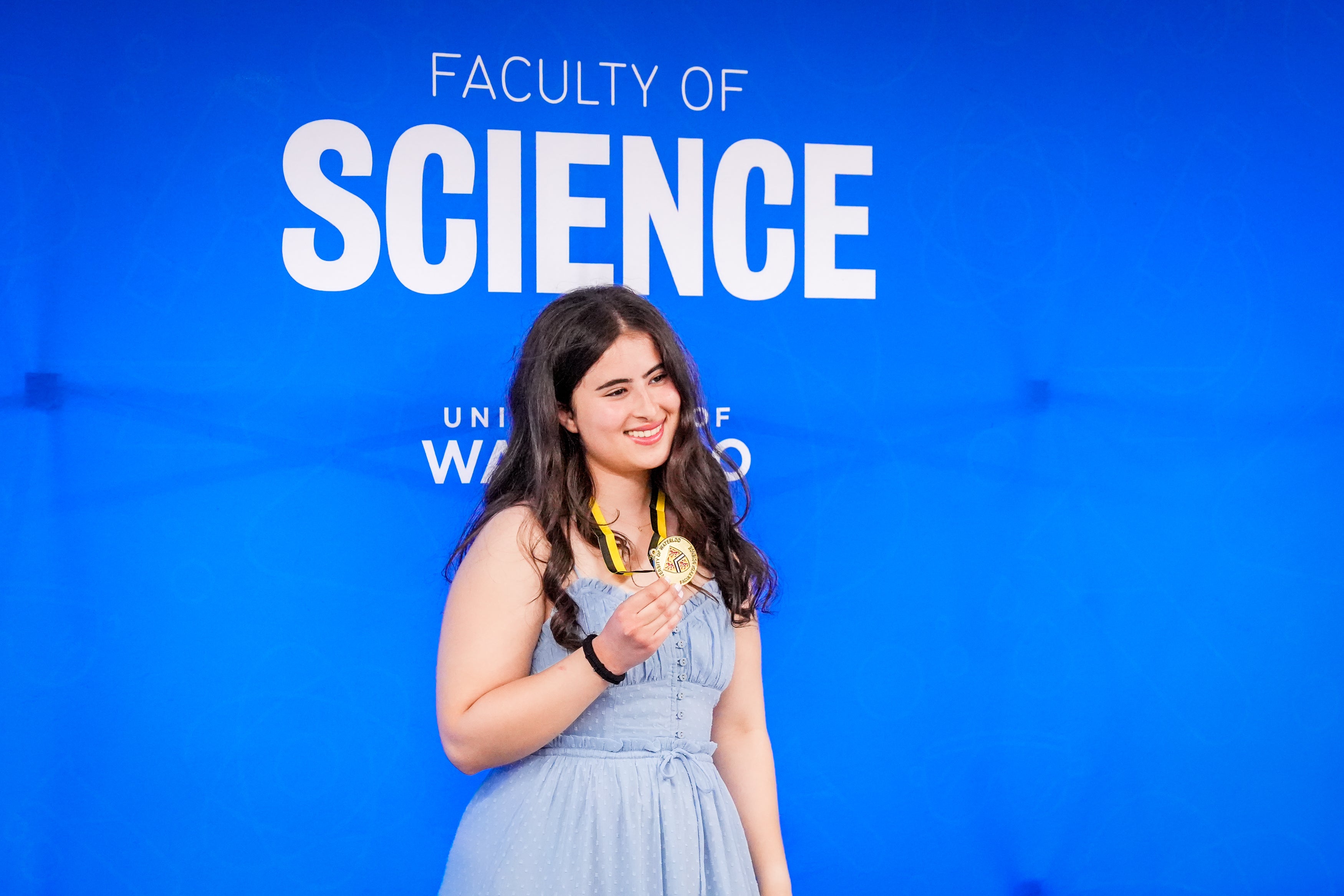 Medal winner smiling in front of Science sign.
