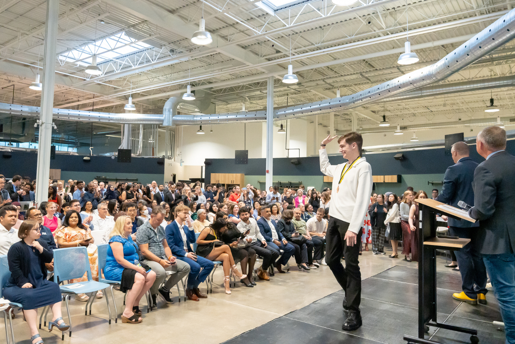 A student waving to a crowd of people at the IDEAL Scholar ceremony.
