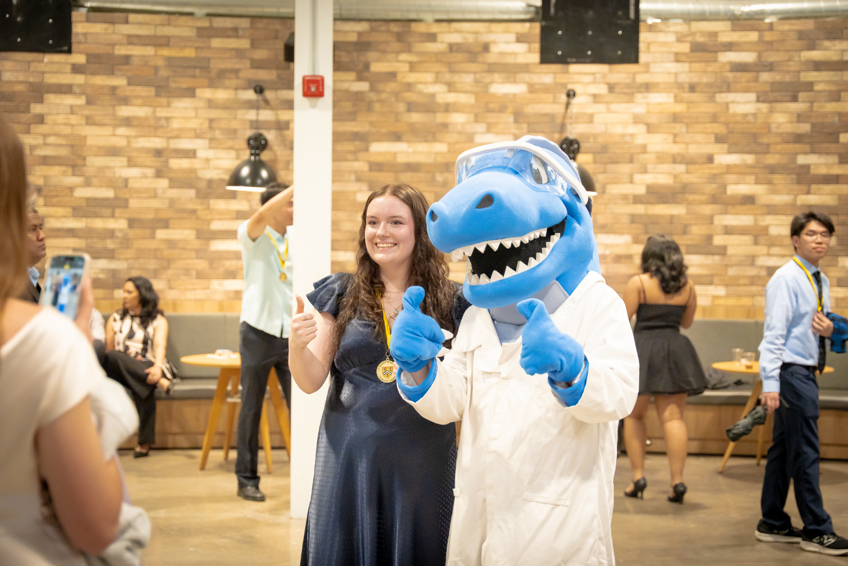 A student posing with the Science mascot Cobalt at the IDEAL Scholar ceremony.