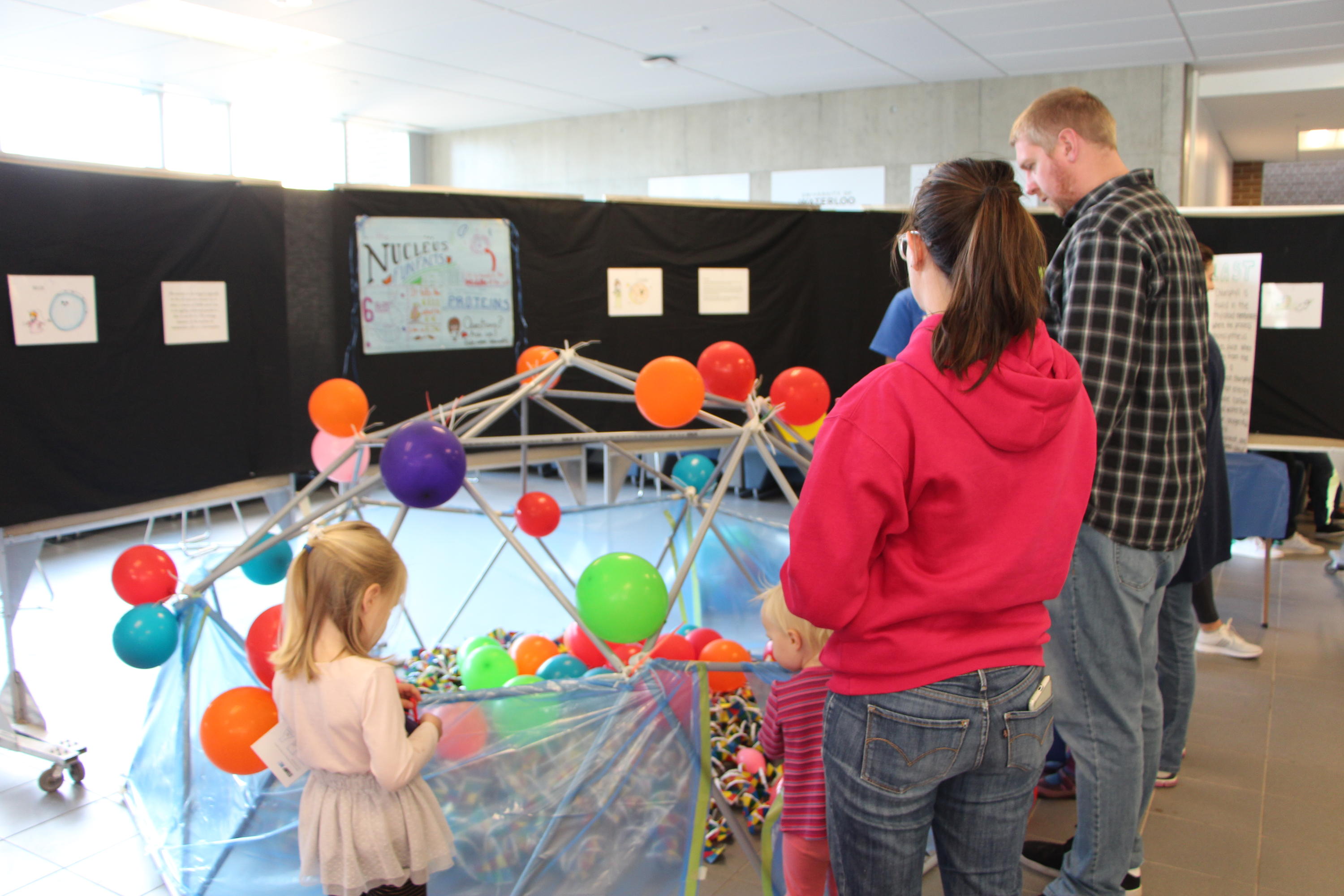 Child and parents exploring a giant model nucleus.