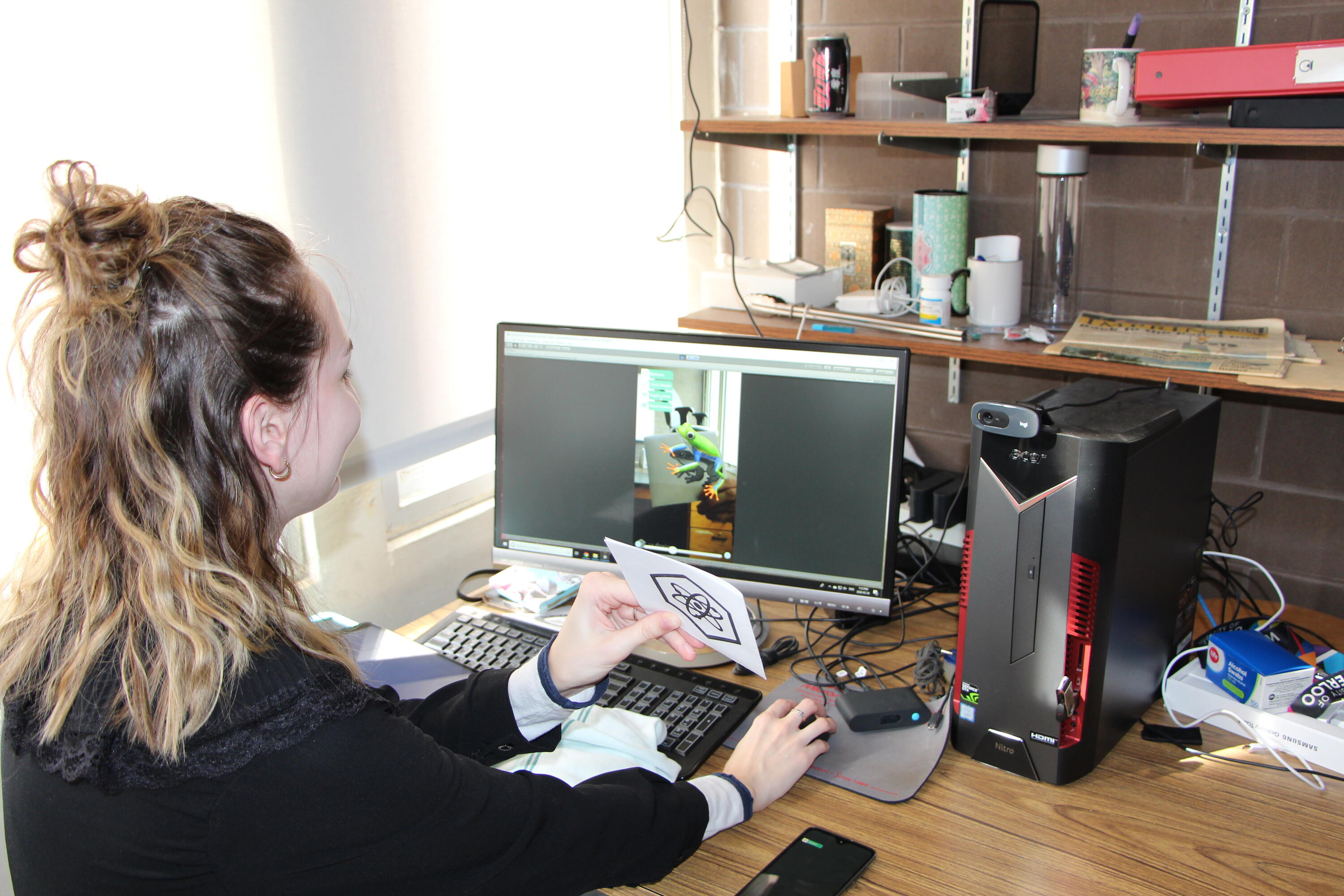 A student looking at a frog artificial reality image on a computer