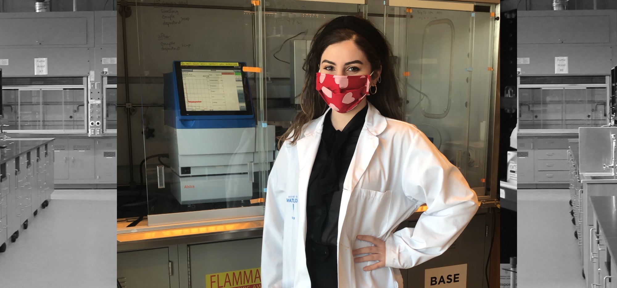 Lilian Toma in the lab wearing a mask and standing in front of a fume hood
